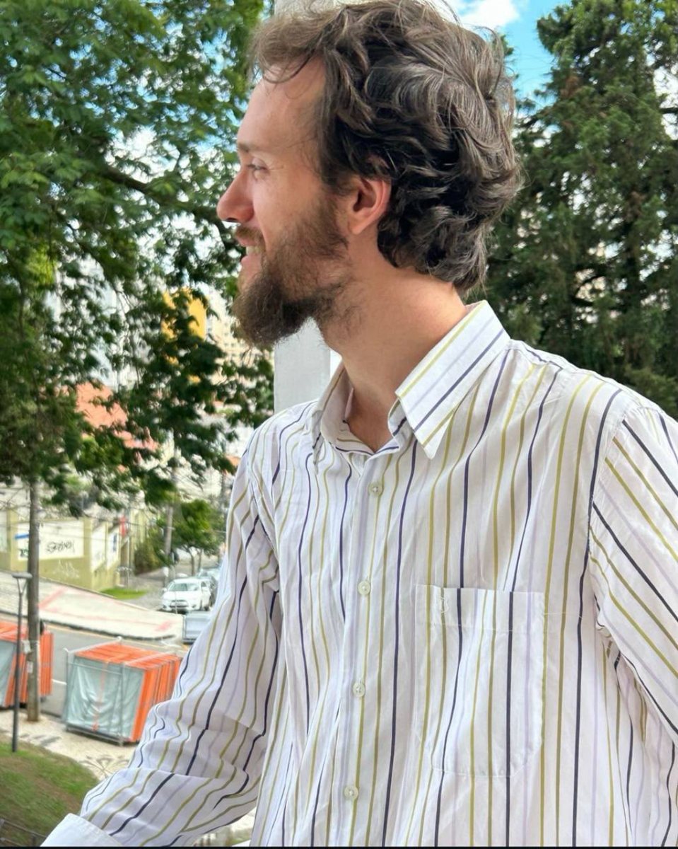 Marcos Nazario de perfil, ao ar livre, cercado por árvores